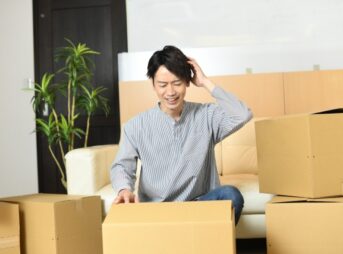 グッズの梱包に悩む男性